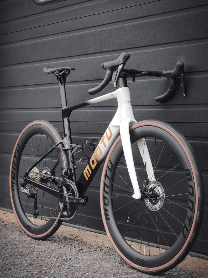 Montu Nui V2, drive side, black-to-white gradient with gold accents on Montu carbon wheels
